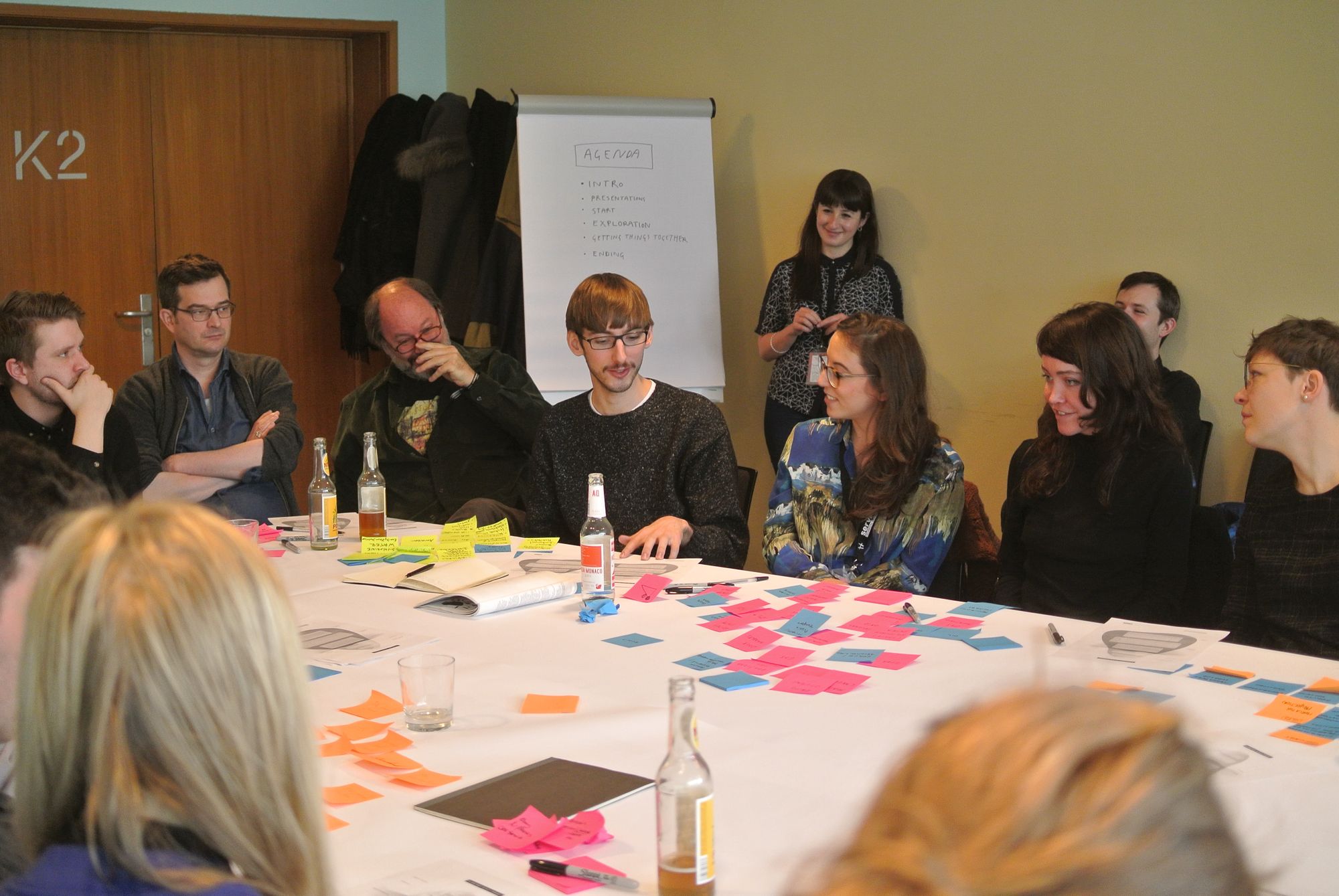 A photograph of a group of people sitting at a table discussing ideas shared on post its at transmediale festival in berlin